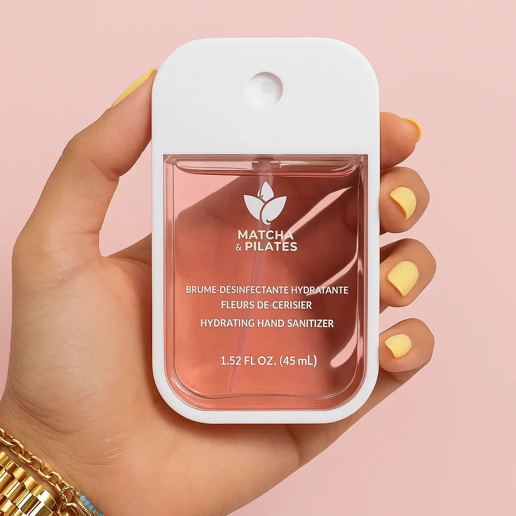 Brume désinfectante hydratante Matcha & Pilates tenue en main, fond rose, soins bien-être.