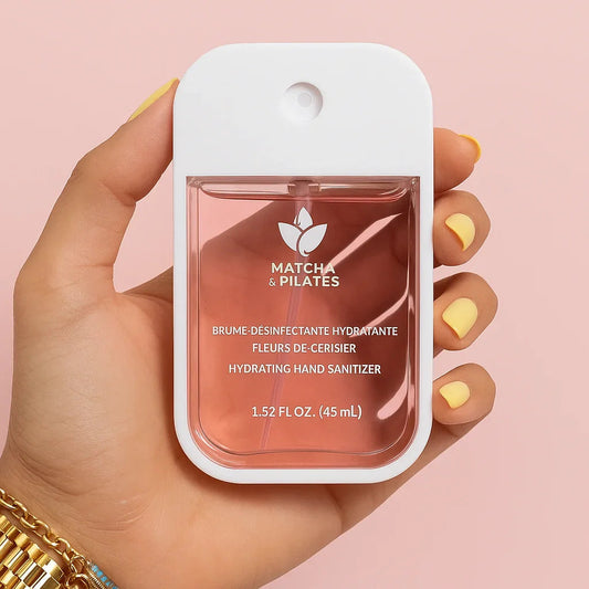 Brume désinfectante hydratante Matcha & Pilates tenue en main, fond rose, soins bien-être.