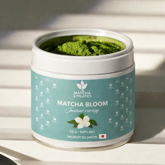 Boîte de matcha bio Matcha & Pilates Matcha Bloom sur table, poudre verte visible, produit japonais.