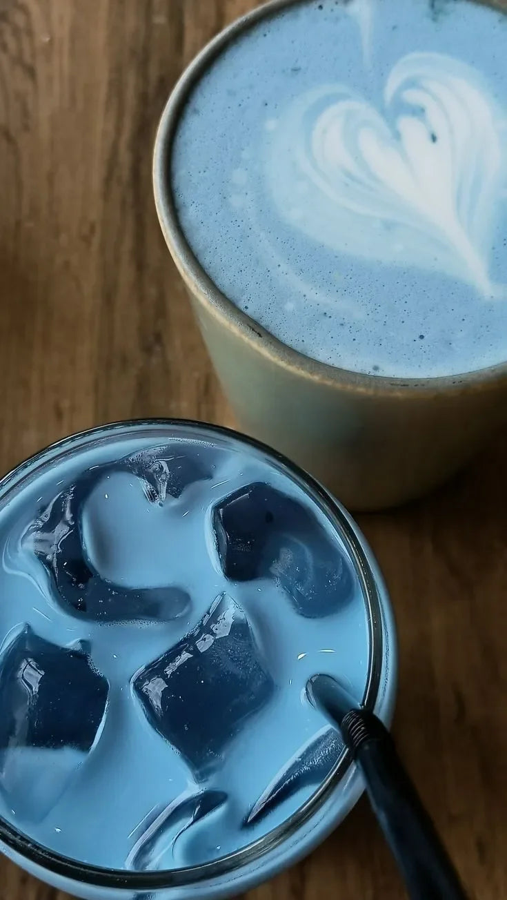 Moon latte bleu chaud avec art latte et boisson glacée au même latte bleu sur table en bois