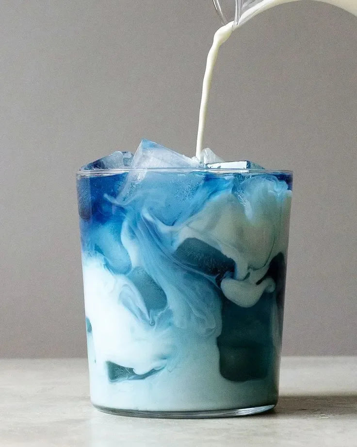 Boisson glacée au lait bleu avec glaçons dans un verre transparent.